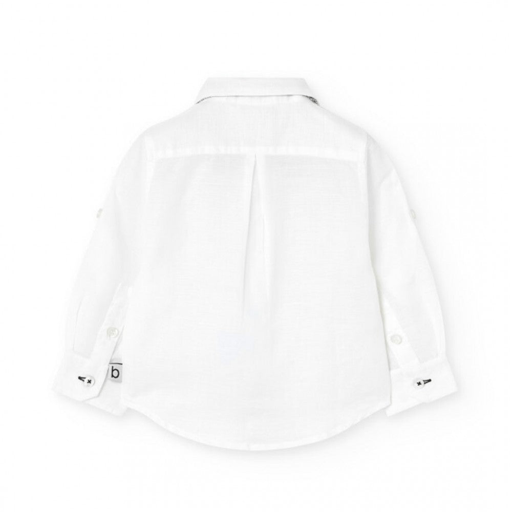 Vista trasera de camisa blanca de manga larga para niño, con detalles elegantes y costuras finas.