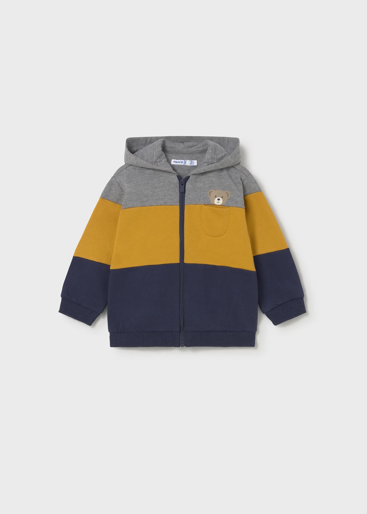 Vista frontal de una sudadera con capucha y cremallera para bebé, con bloques de color gris, amarillo y azul marino, y un bolsillo con un osito, marca Mayoral.