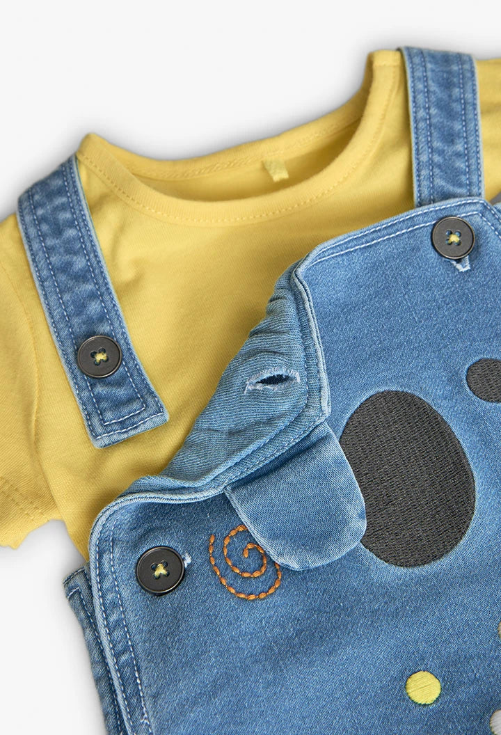 Detalle del conjunto de bebé con camiseta amarilla y tirantes de mezclilla azul con botones.