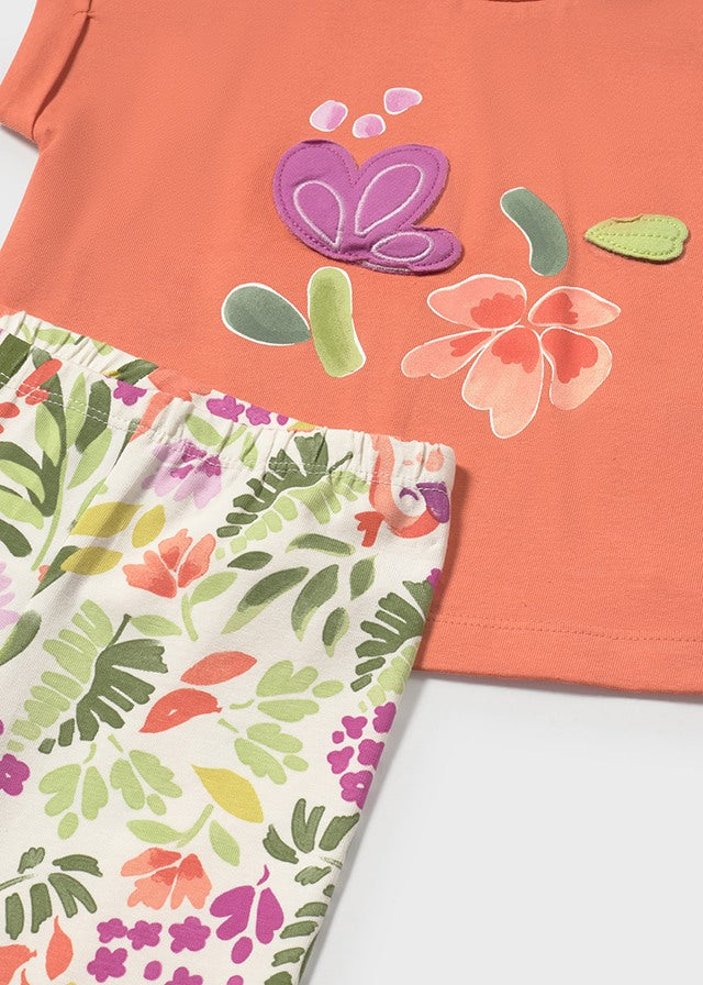 Detalle de conjunto para niña con blusa naranja y leggings estampados con motivos florales y mariposas.