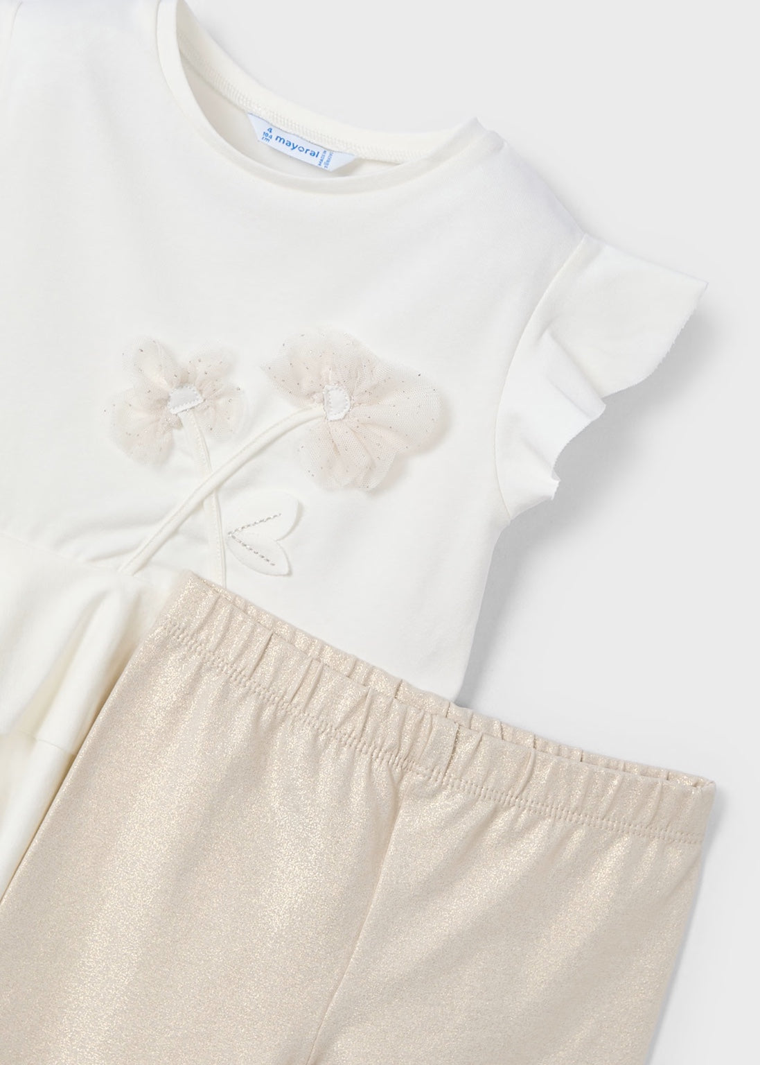 Detalle de la playera con flores bordadas en relieve y leggings brillosos del conjunto de niña de Mayoral.