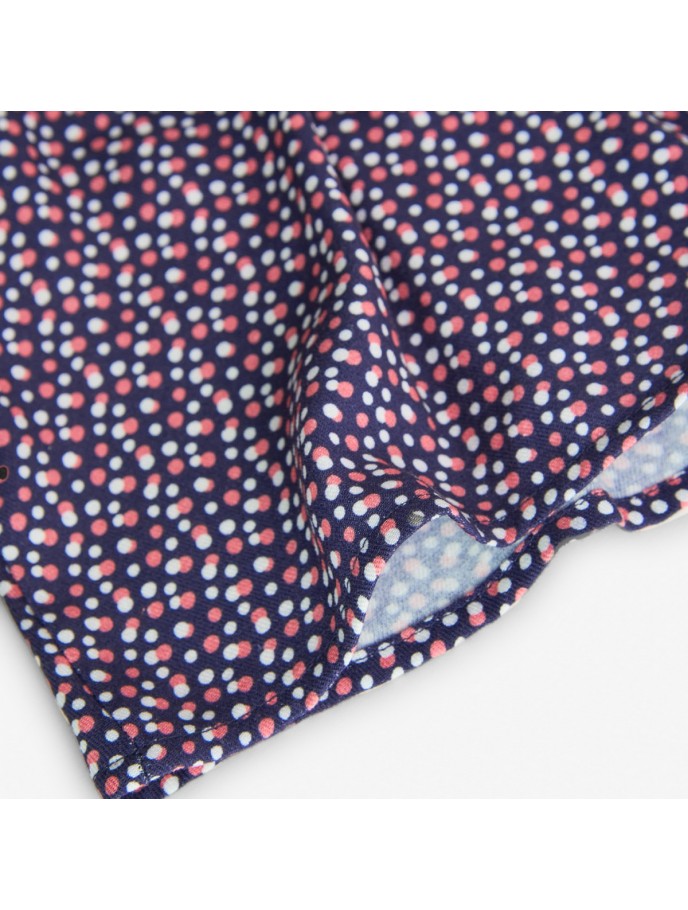 Detalle de la tela de la blusa estampada Boboli de Cachaboo, con fondo azul marino y estampado de pequeños lunares en tonos rosa y blanco.