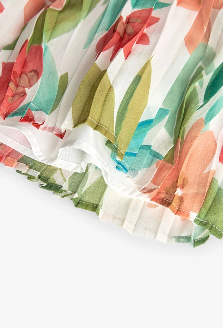 Detalle del vuelo inferior de falda plisada de gasa con estampado floral colorido.