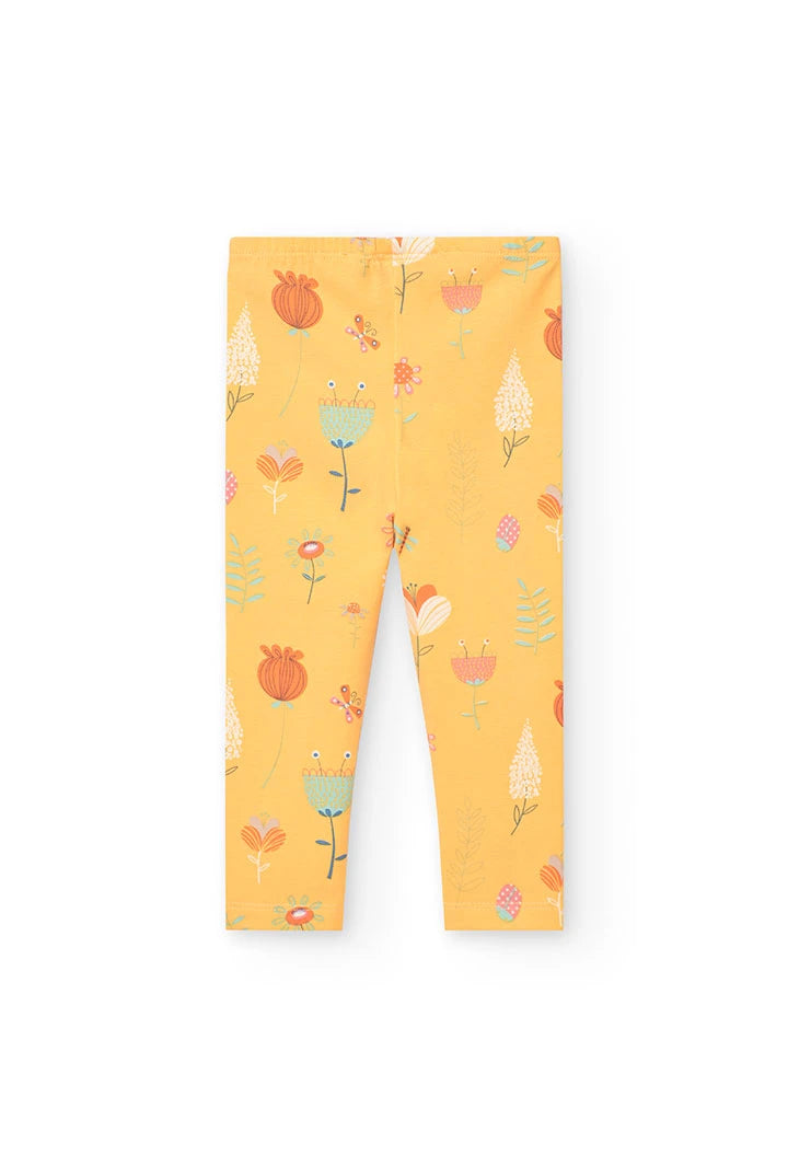 Leggings amarillos con estampado floral y detalles de insectos, vistos desde la parte trasera.