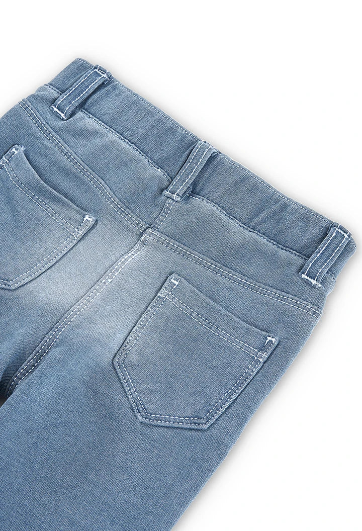 Bolsillos traseros de leggings tipo jeans azul claro para niña, con costuras blancas visibles.