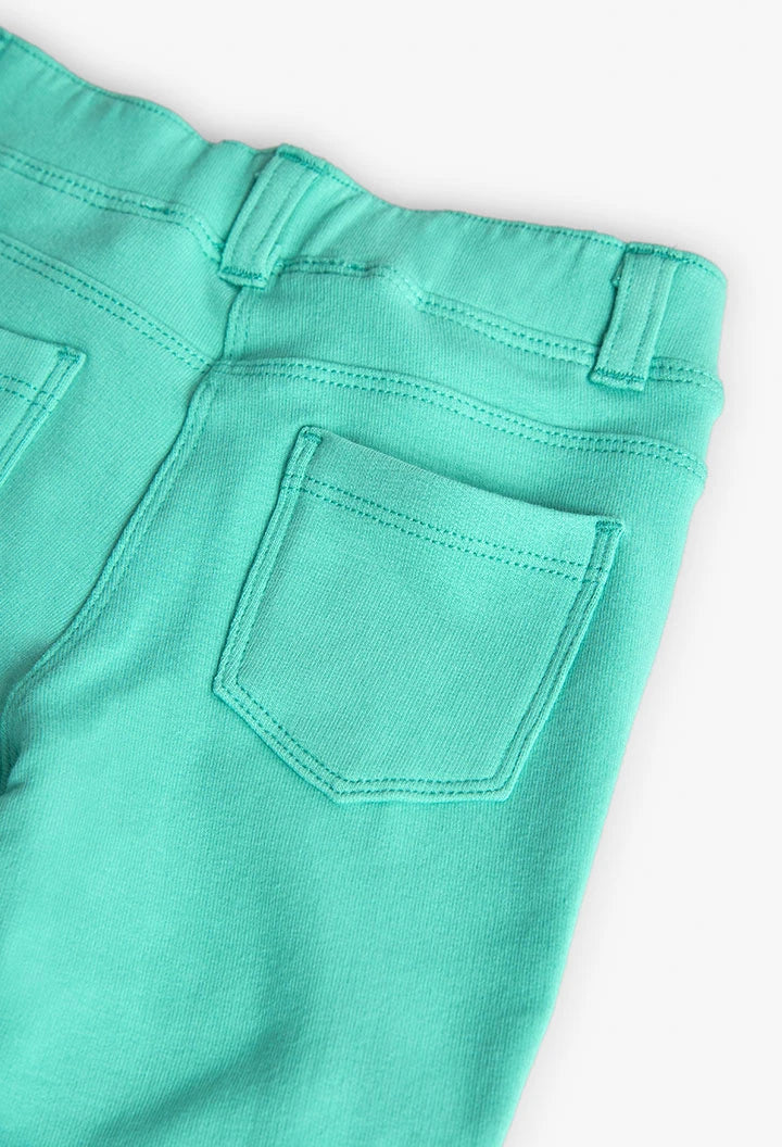 Vista trasera de los leggings verde menta, mostrando los bolsillos decorativos y la pretina elástica.