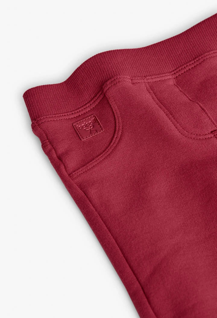 Detalle del bolsillo frontal falso y la placa de la marca en unos jeggings de felpa color guinda, marca Boboli.