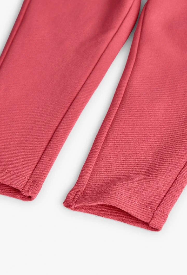 Detalle del dobladillo de unos jeggings de felpa color coral para niña.