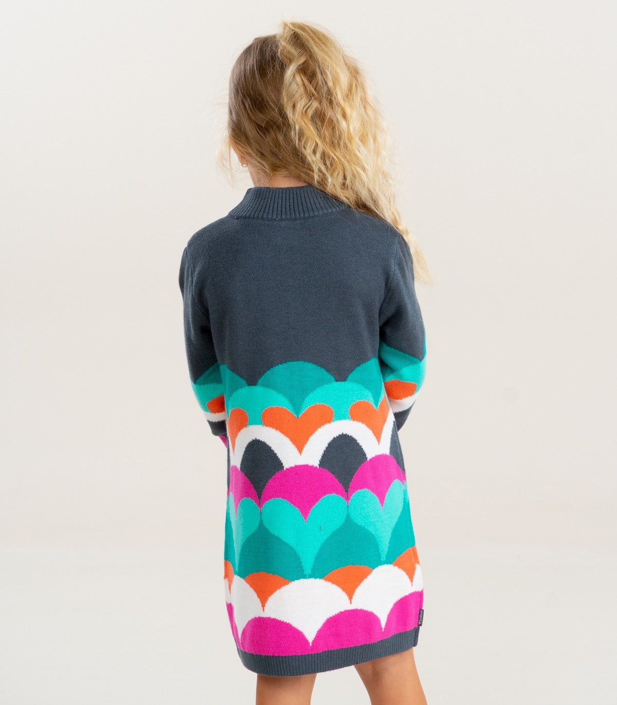 Vista trasera del vestido tejido Boboli con diseño de corazones de colores, en modelo infantil.