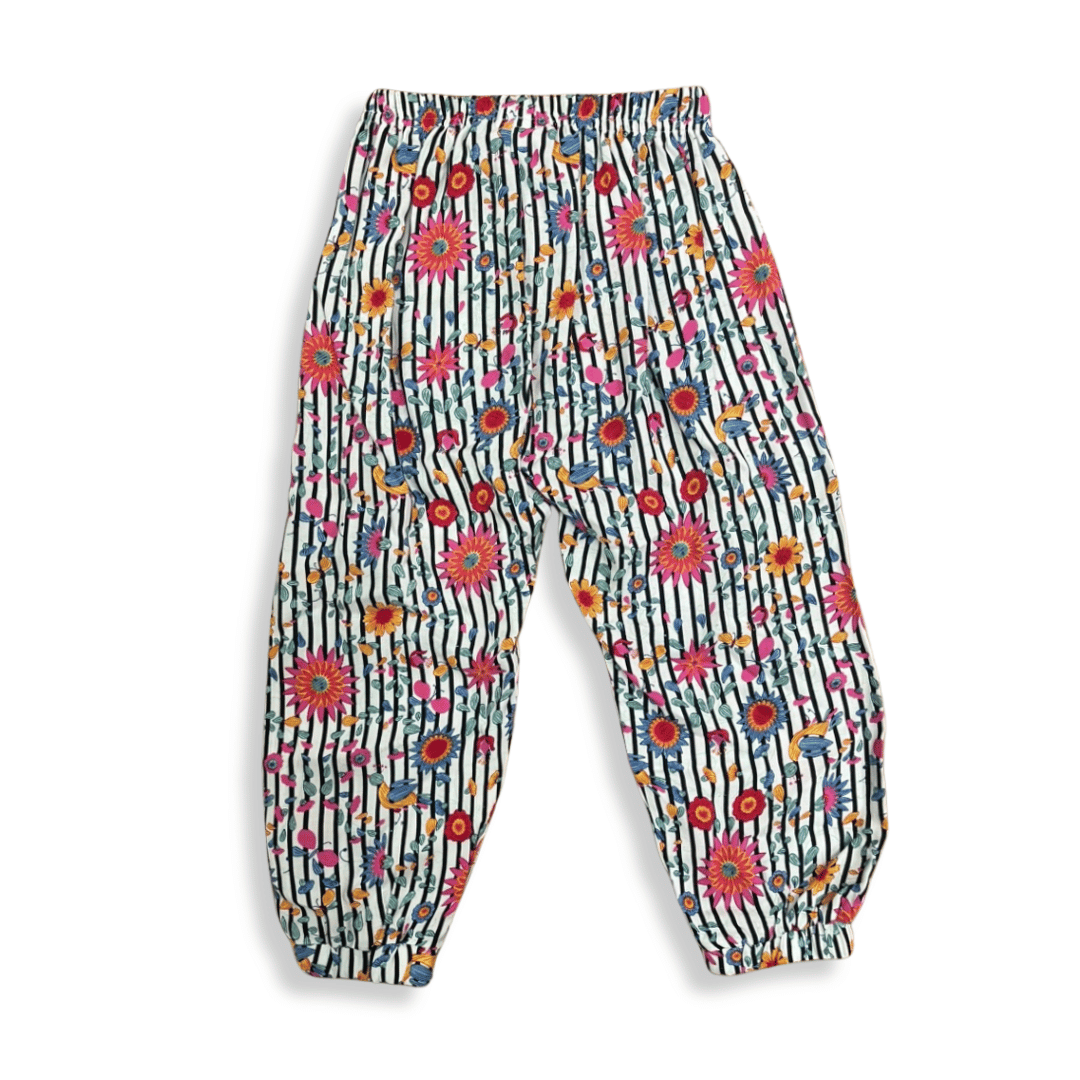Pantalón infantil holgado con estampado de flores y rayas en tonos vibrantes, diseñado con resorte en la cintura y tobillos para mayor comodidad y estilo tropical.