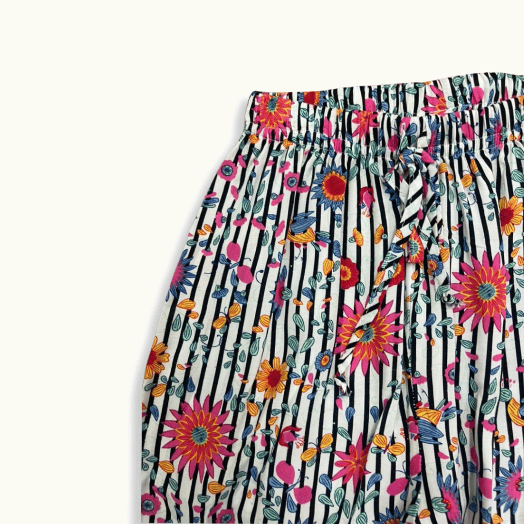 Detalle del pantalón infantil con estampado tropical de flores y rayas, resorte en la cintura y lazo ajustable para mayor comodidad y estilo vibrante.