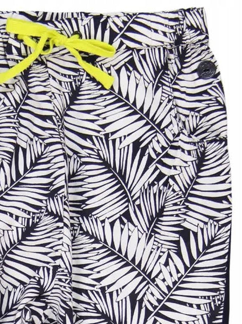 Detalle del pantalón estampado con hojas negras y blancas, con moño amarillo neón y botón decorativo.