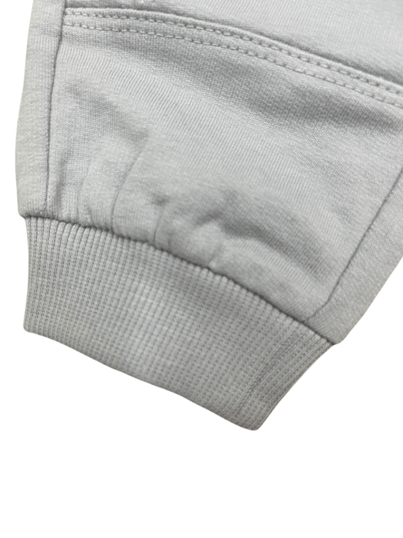 Detalle del puño acanalado del pantalón deportivo gris para niños, con costuras reforzadas y tela de algodón suave.