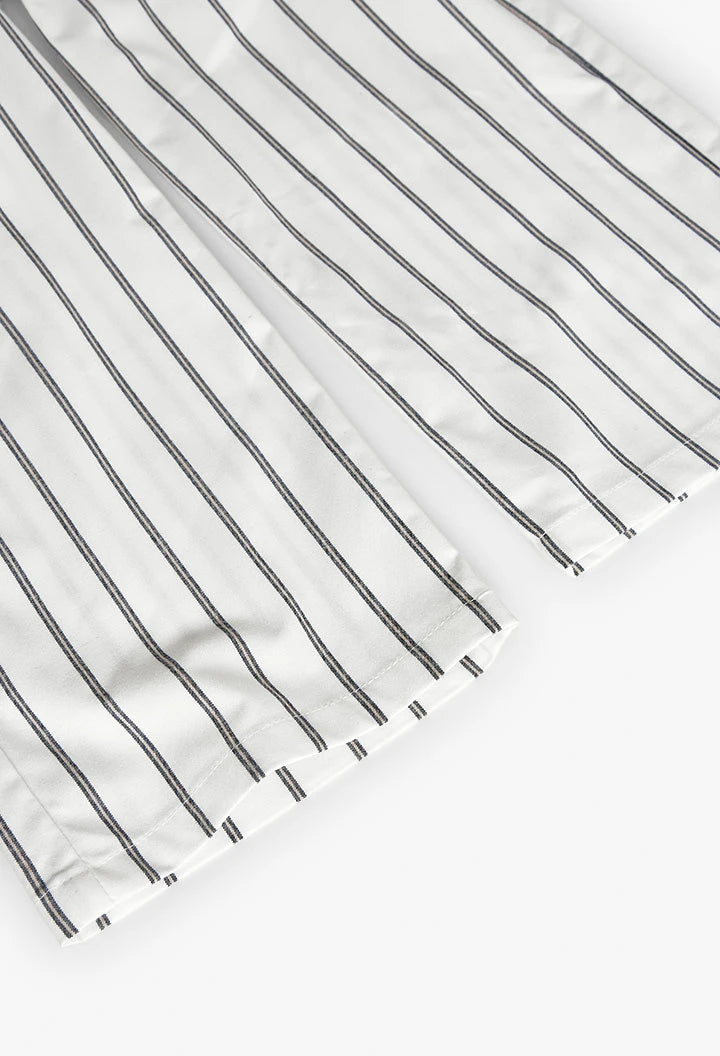 Dobladillo del pantalón blanco con rayas verticales negras.