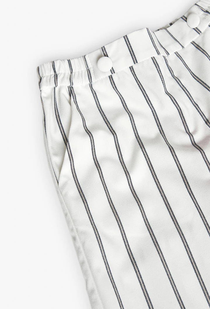 Detalle de cintura elástica con botones decorativos del pantalón rayado.