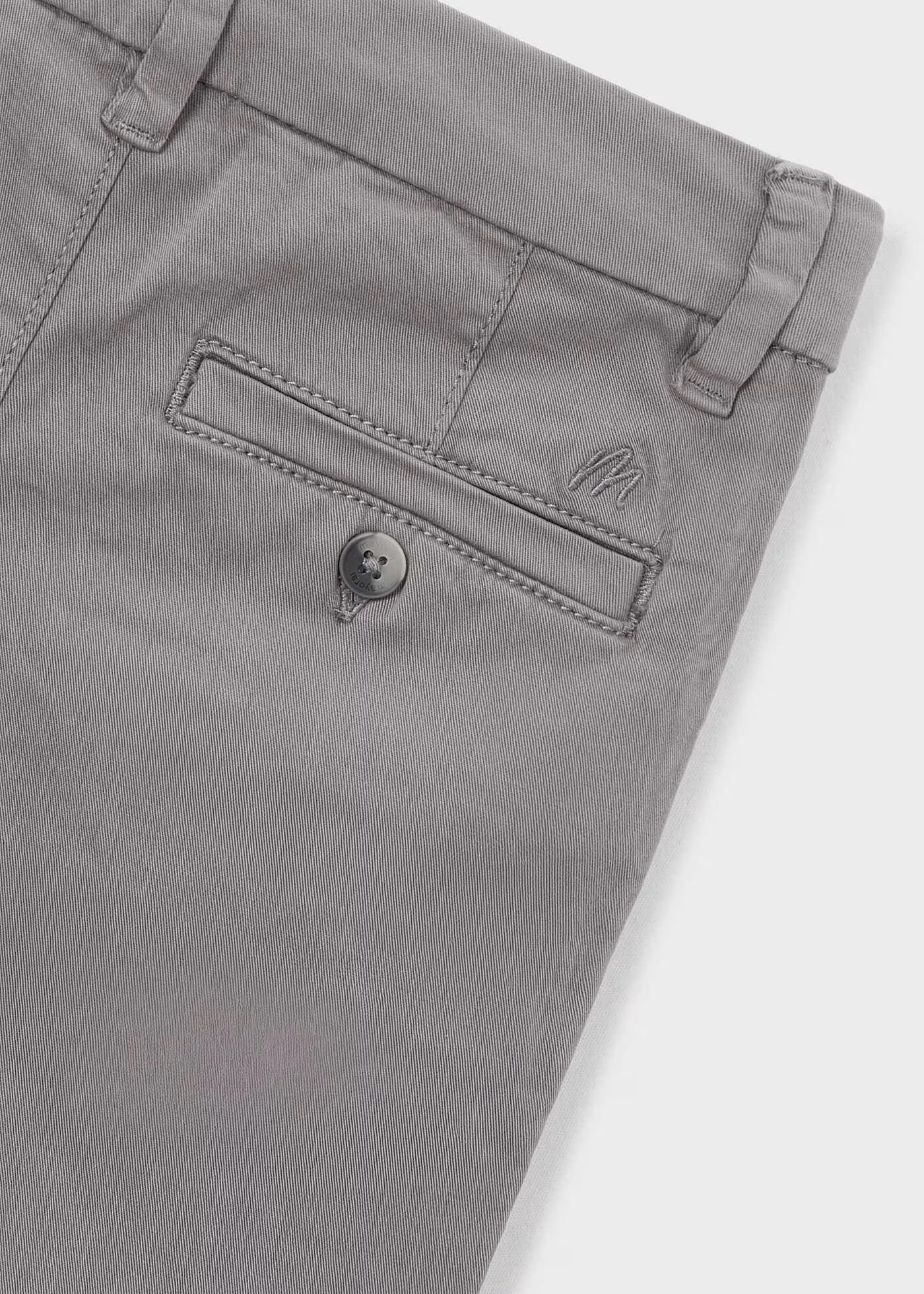 Detalle del bolsillo trasero con botón y el logo bordado de un pantalón chino gris, marca Mayoral.