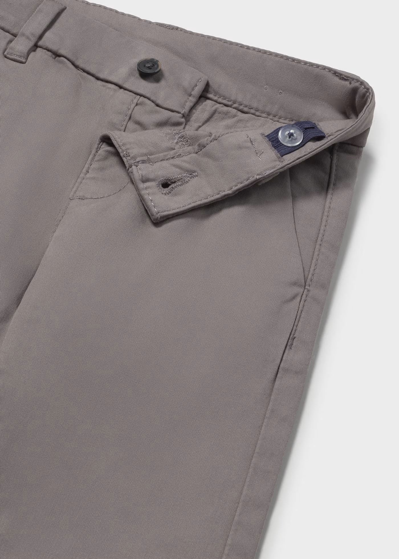 Detalle del botón y la cintura interior ajustable de un pantalón chino gris para niño.