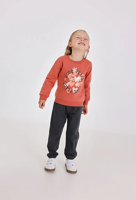 Niña riendo con la cabeza hacia atrás, usando un conjunto de sudadera color teja y pants oscuros, marca Boboli.
