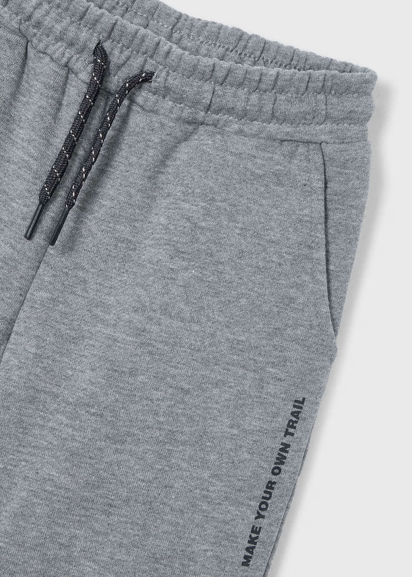 Detalle de la cintura y el estampado "MAKE YOUR OWN TRAIL" en un pantalón jogger de felpa color gris claro, marca Mayoral.