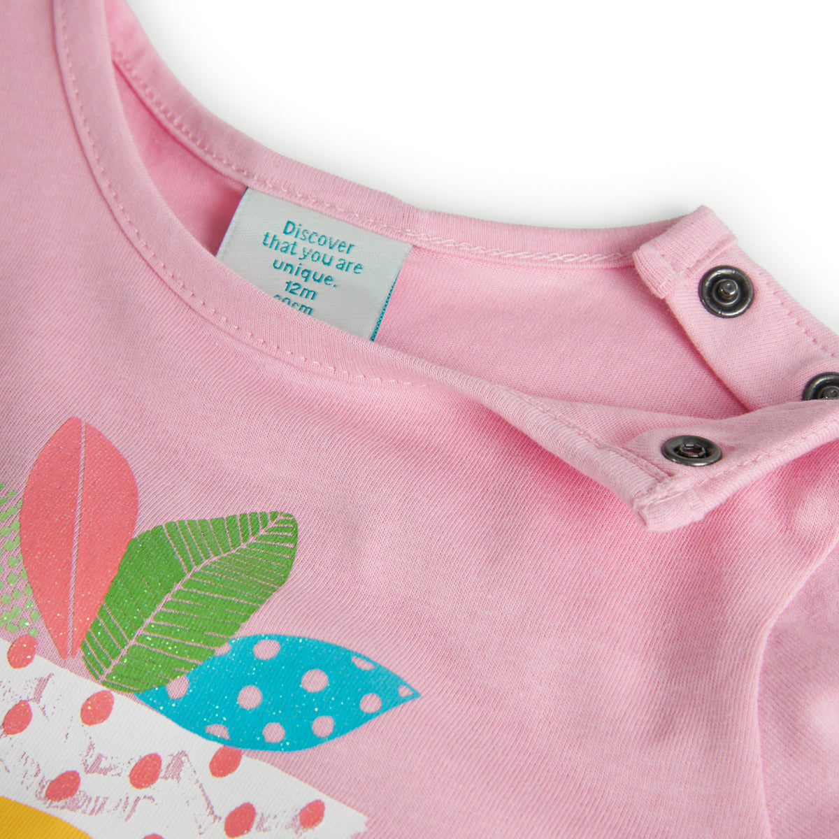 Detalle de la blusa rosa infantil de Boboli con botones en el hombro para facilitar el cambio de ropa. Diseño en algodón con estampado colorido y textura suave.