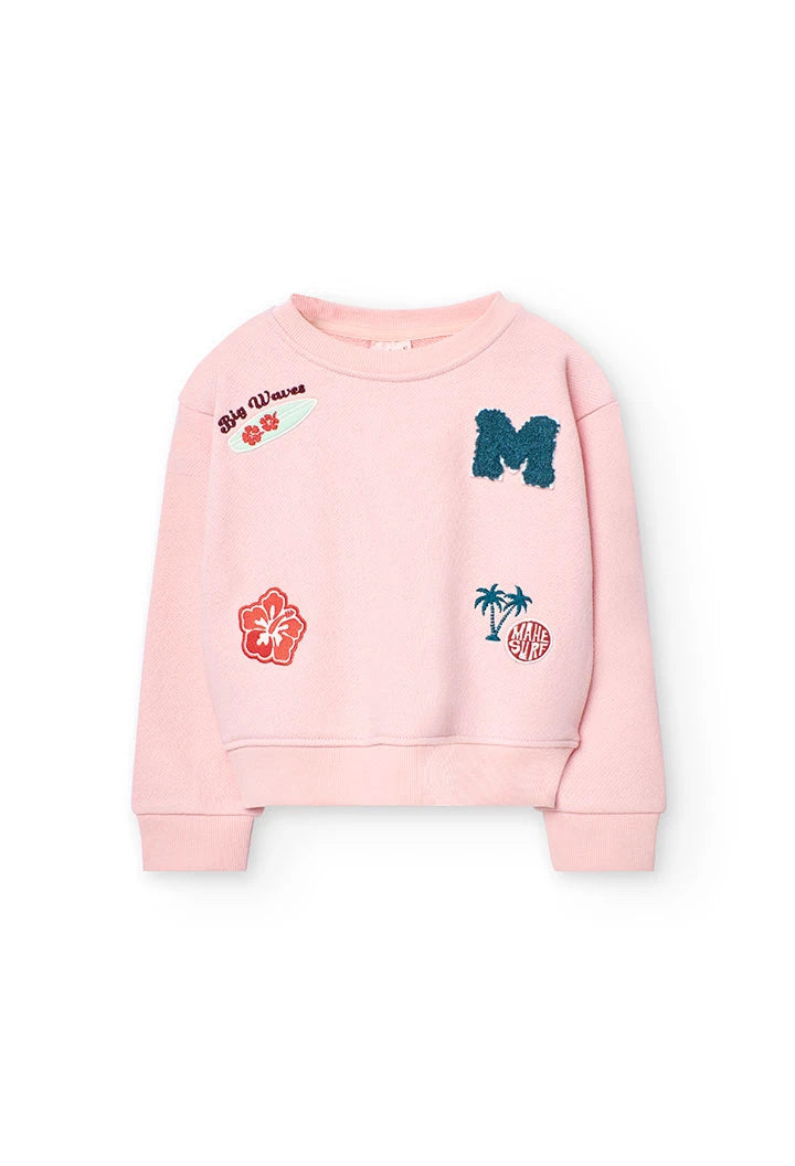 Vista frontal de sudadera rosa de niña con parches decorativos de estilo surf.