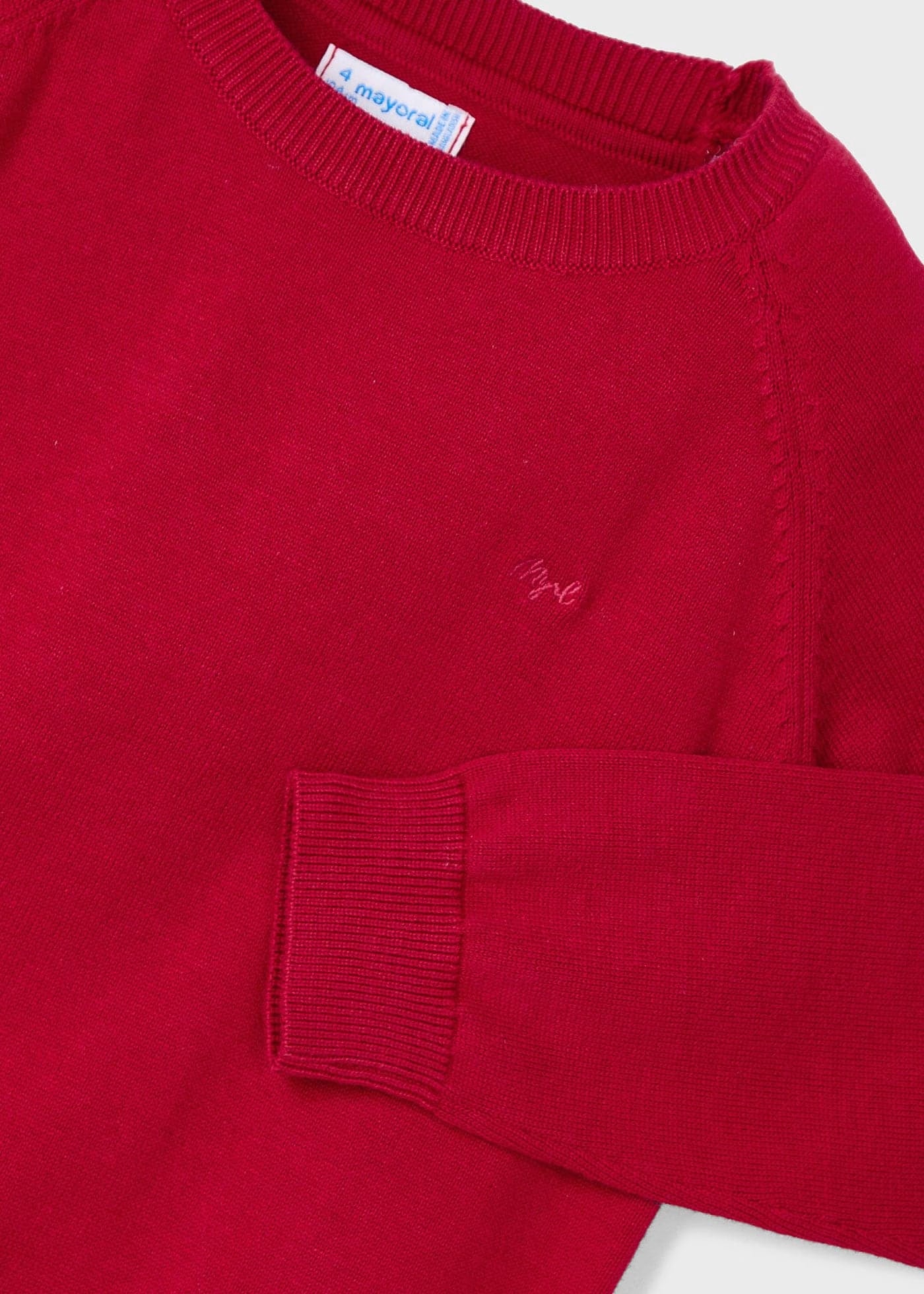 Detalle del cuello, hombro y puño de un suéter rojo de tricot Mayoral, mostrando la textura del tejido y el logotipo bordado en el pecho.