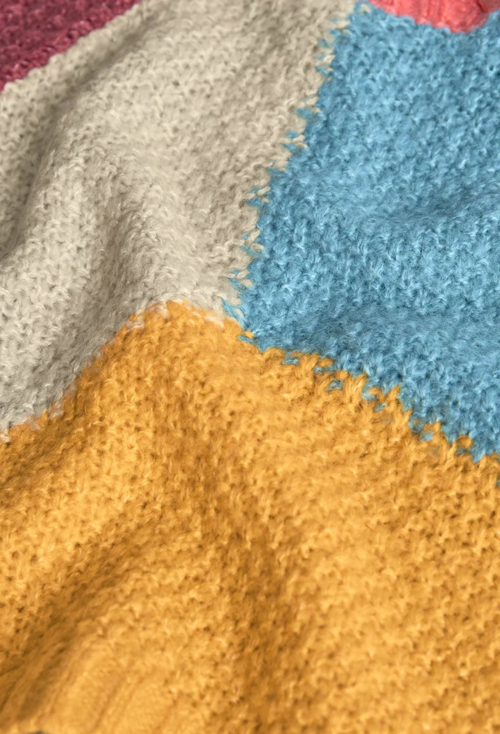 Detalle del tejido texturizado de un suéter con parches de color azul, amarillo y gris, marca Boboli.