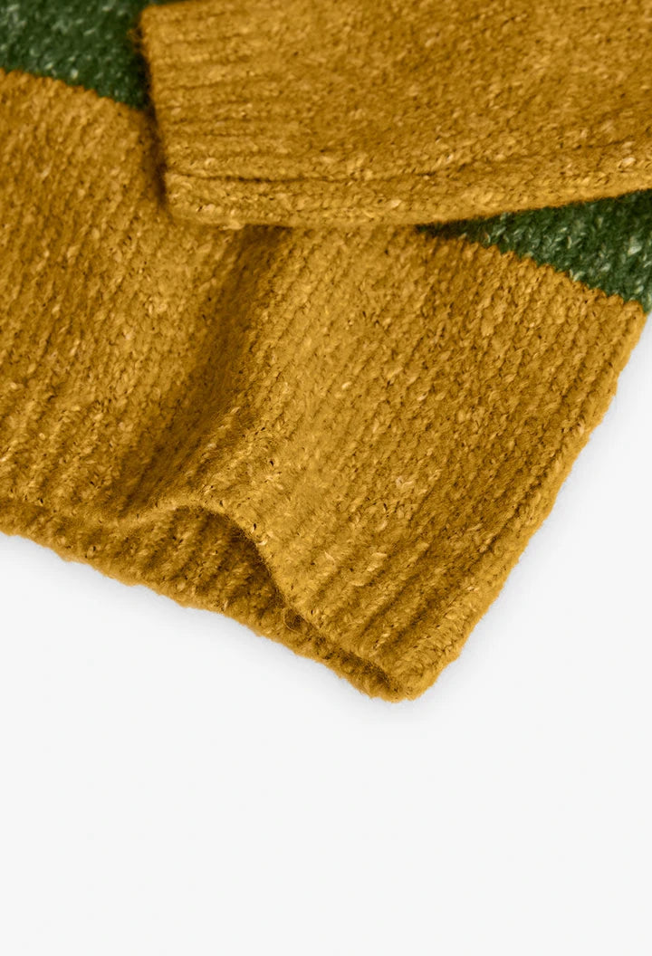 Detalle del puño y la textura bouclé de un suéter de punto color amarillo ocre, marca Boboli.