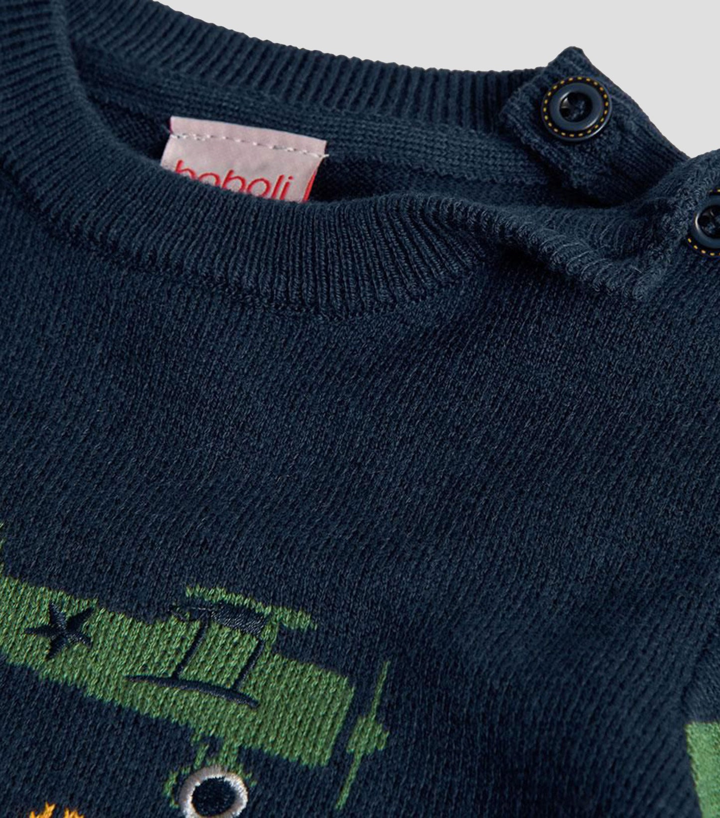 Detalle del cuello redondo y los botones en el hombro de un suéter de punto azul marino para niño, marca Boboli.
