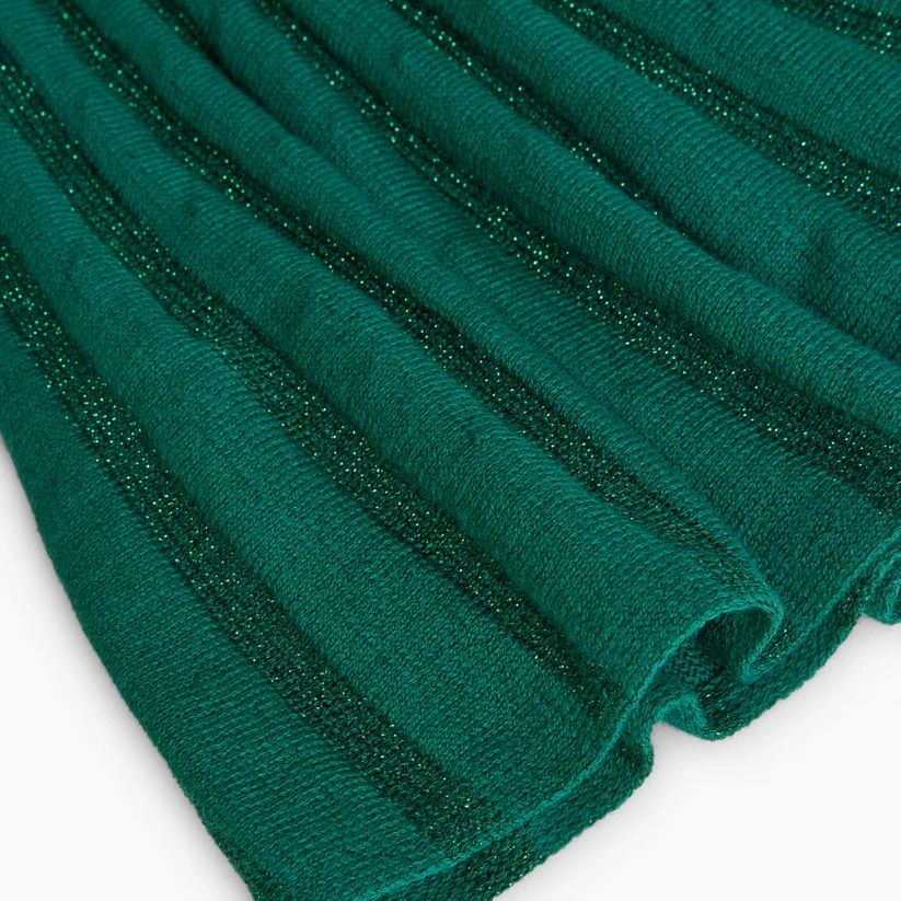 Detalle de la falda plisada en tejido verde brillante del vestido Boboli con textura metálica.