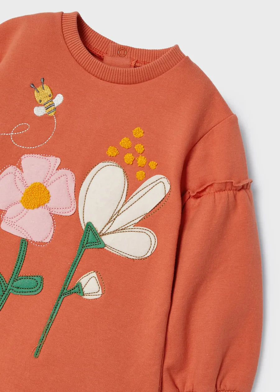 Detalle del bordado en vestido naranja: flor blanca, flor rosa, abejita y aplicaciones en hilo amarillo y verde