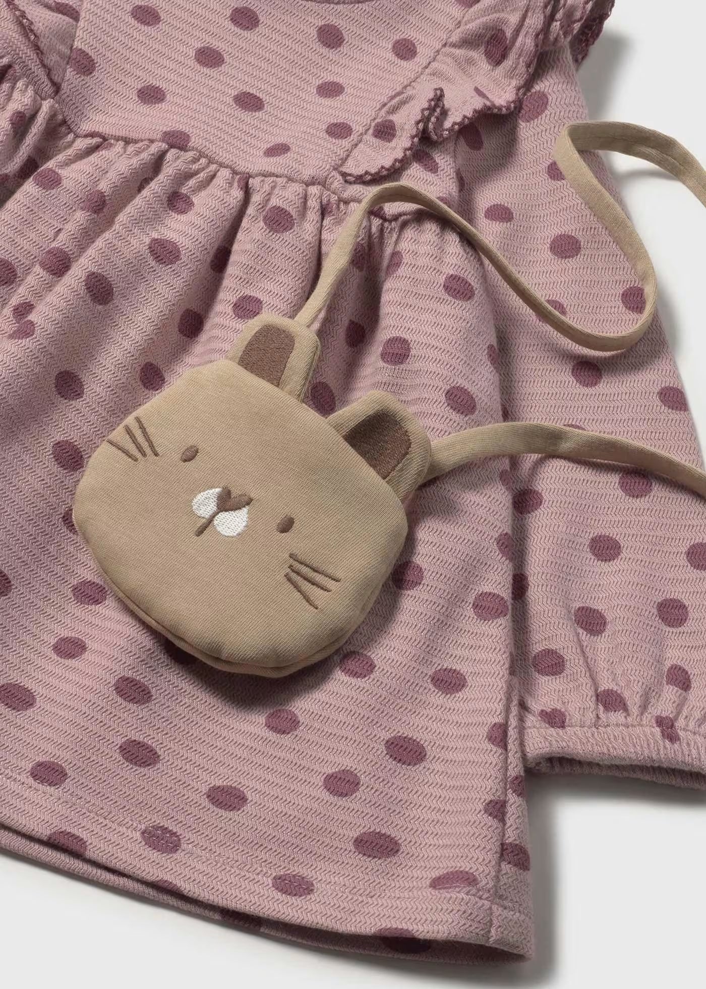 Detalle de la bolsita con cara de gatito sobre el vestido de punto con lunares, marca Mayoral.