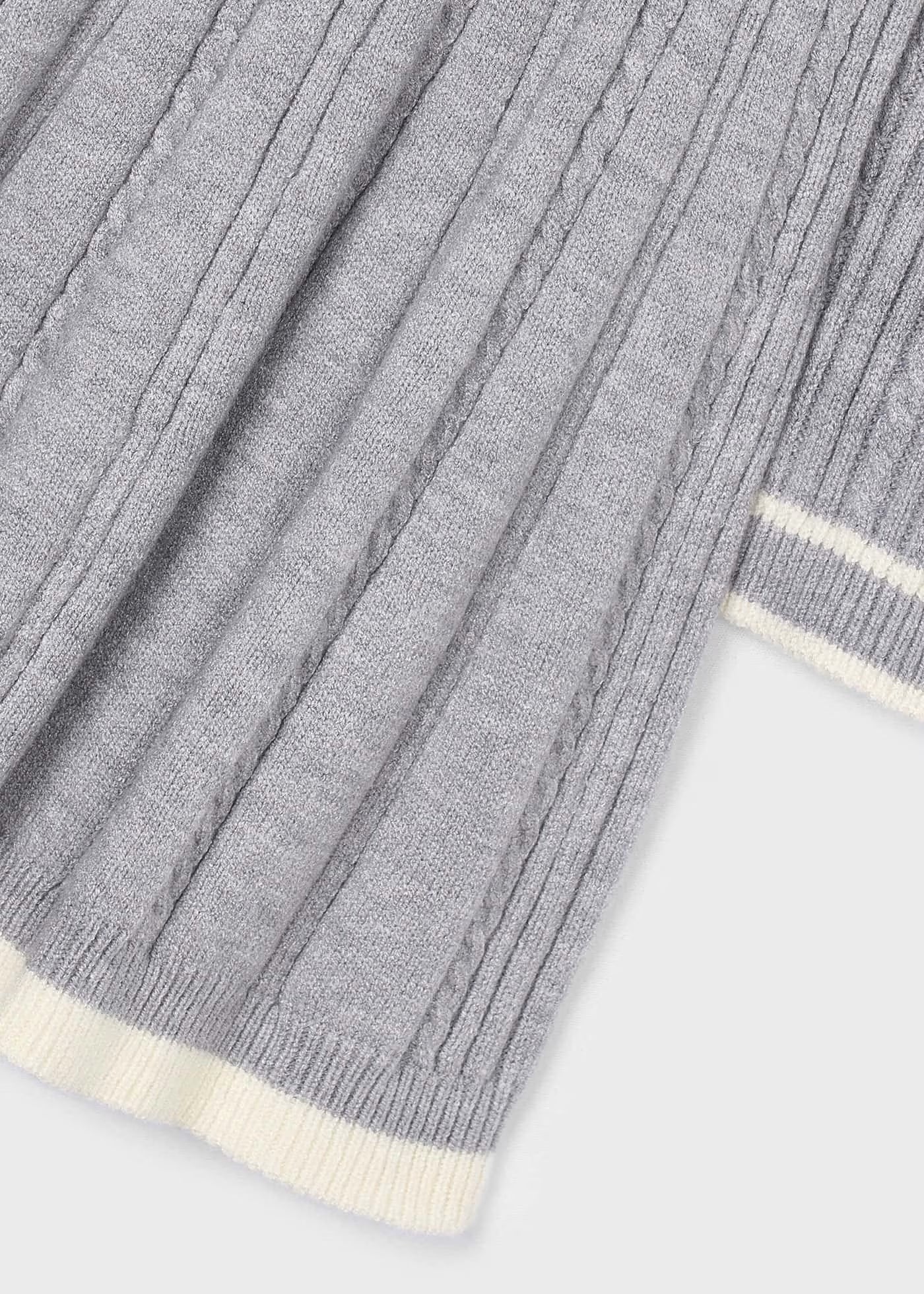 Detalle del tejido trenzado y el bajo a contraste de un vestido de punto gris, marca Mayoral.