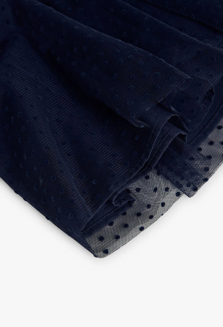 Primer plano de la falda de tul azul marino con estampado de puntos (plumetis) de un vestido para niña.