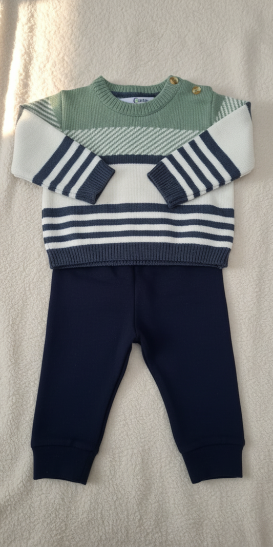 Conjunto de dos piezas de punto para bebé sobre un fondo de tela suave: un suéter con rayas horizontales en verde, blanco y azul marino, y un pantalón liso a juego en azul marino.