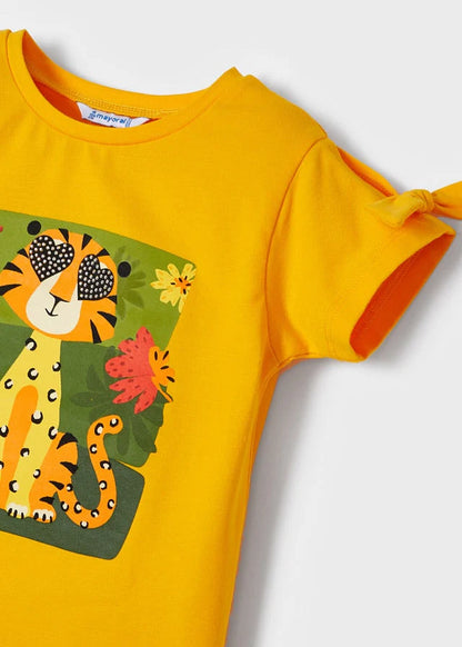 Detalle de blusa infantil amarilla con estampado de tigre en la selva y lazo decorativo en la manga, confeccionada en algodón suave para mayor comodidad.