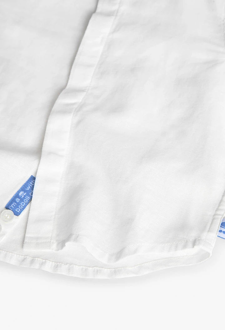 Detalle inferior de camisa blanca de lino para niño con etiqueta azul de Boboli.