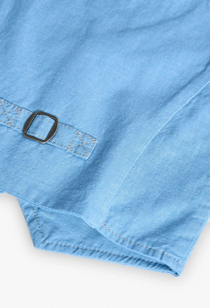 Detalle de hebilla ajustable en la parte trasera del chaleco de lino azul para niño.