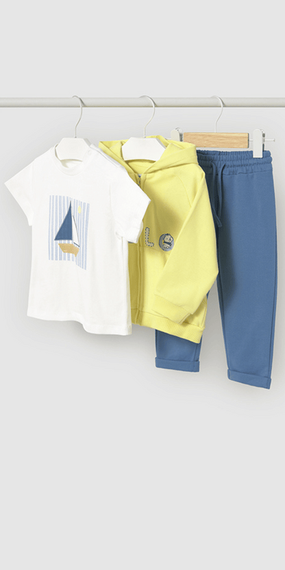 Conjunto de ropa para bebé colgado en perchas, compuesto por una camiseta blanca con un diseño de velero sobre fondo de rayas, una sudadera con capucha en color amarillo neón con detalles bordados y un pantalón azul con cintura elástica y puños doblados para mayor comodidad.