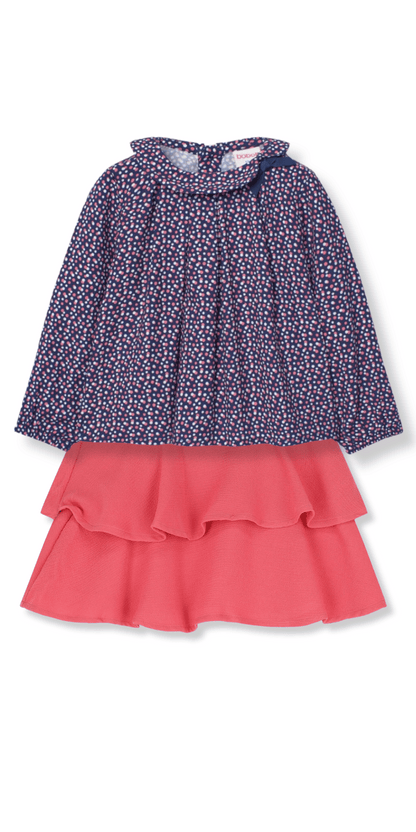 Conjunto para niña con blusa de manga larga azul marino con estampado de lunares y lazo en el cuello, combinado con falda rosa de volantes.