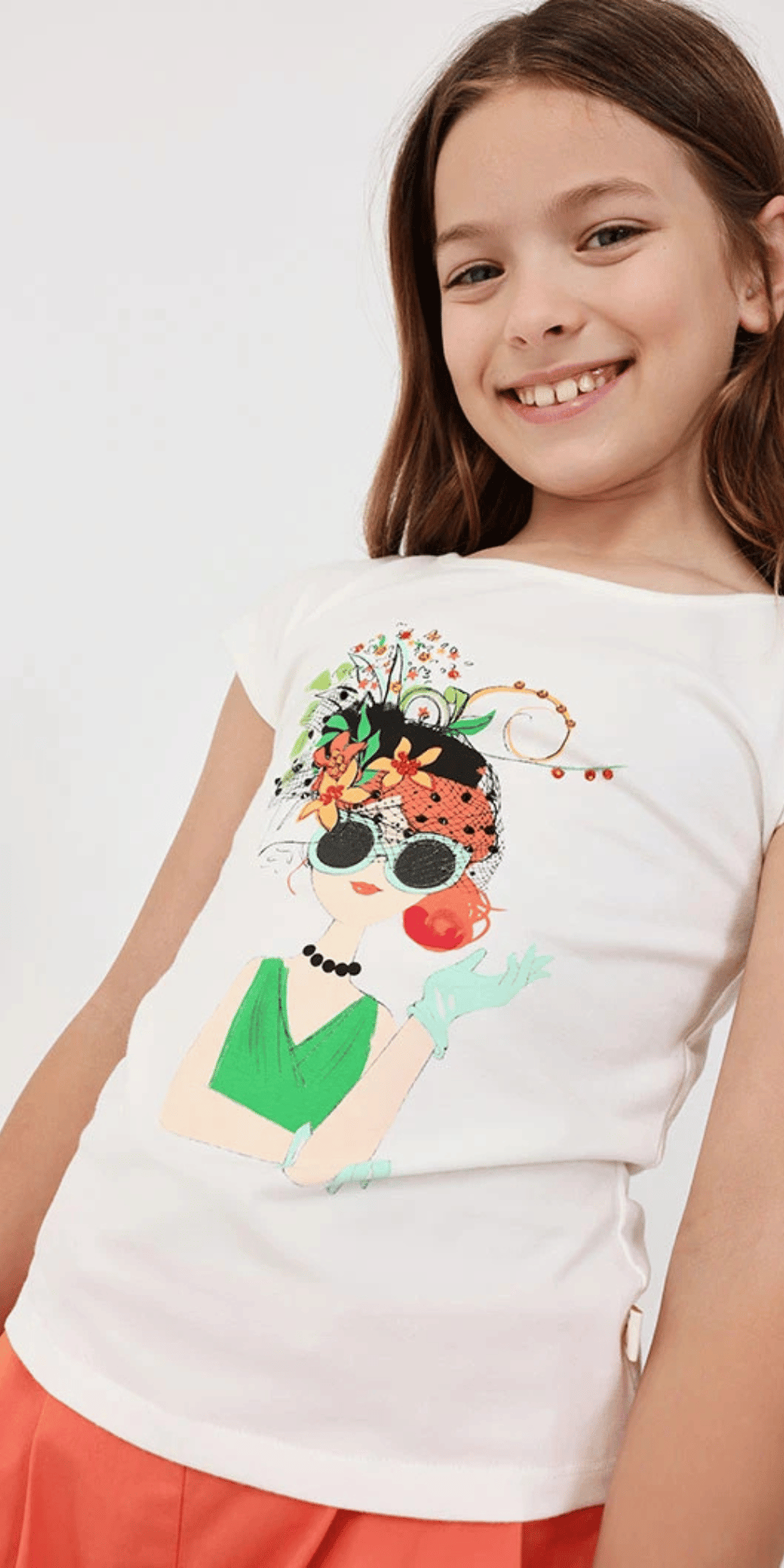 Niña modelando conjunto Boboli con playera blanca y short coral.