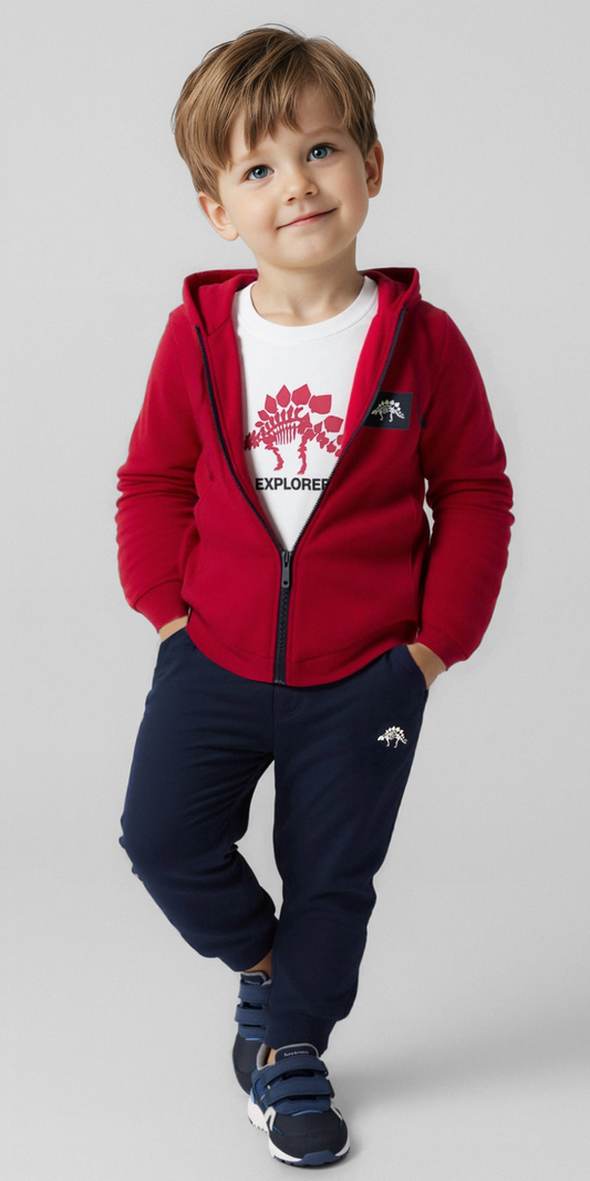 Niño sonriendo con un conjunto de tres piezas: sudadera roja con capucha, playera blanca con dinosaurio y pants azul marino, marca Mayoral.