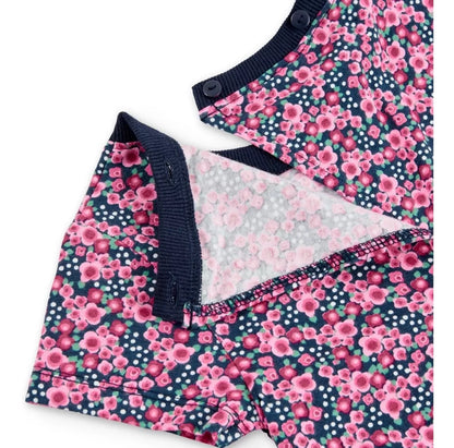 Detalle del cierre de botones en la espalda del jumpsuit corto de Boboli con estampado floral en tonos rosas sobre fondo azul marino. Se muestra la abertura trasera y el ribete elástico en azul marino.