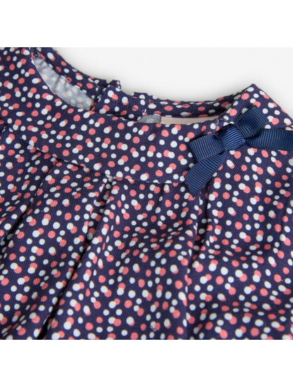 Detalle del cuello de la blusa estampada Boboli de Cachaboo, con lazo decorativo azul y estampado de lunares en tonos rosa y blanco.