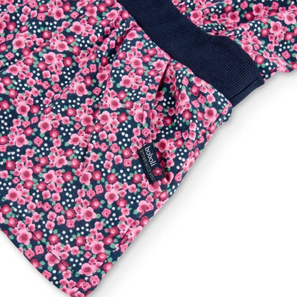Detalle del jumpsuit corto de Boboli con estampado floral en tonos rosas sobre fondo azul marino. Se muestra el bolsillo lateral con etiqueta de la marca y la cintura elástica en color azul marino.