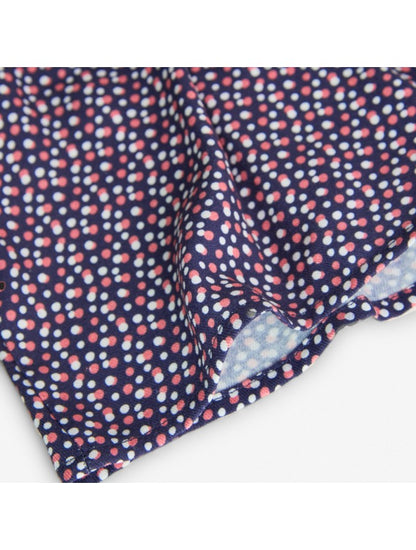 Detalle de la tela de la blusa estampada Boboli de Cachaboo, con fondo azul marino y estampado de pequeños lunares en tonos rosa y blanco.
