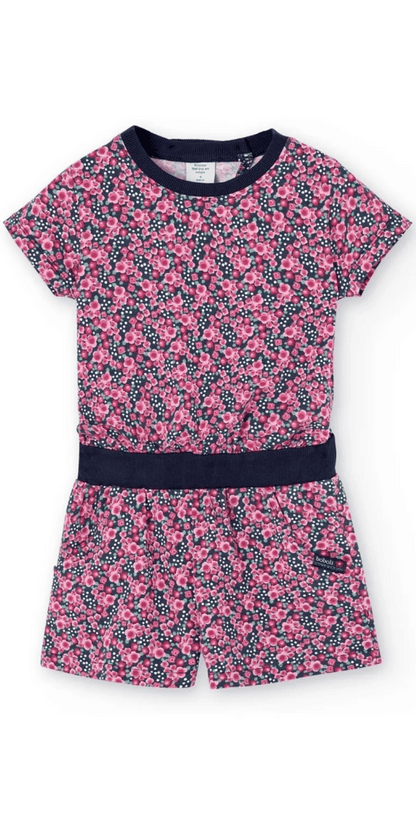 Jumpsuit corto de Boboli con estampado floral en tonos rosas sobre fondo azul marino. Diseño de manga corta, cintura elástica con banda azul y bolsillos laterales.
