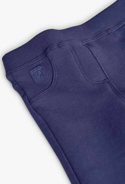 Detalle del bolsillo frontal falso y la placa de la marca en unos jeggings de felpa color morado, marca Boboli.