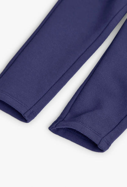 Detalle del dobladillo de unos jeggings de felpa color morado para niña.