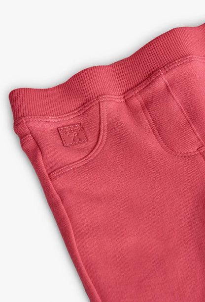 Detalle del bolsillo frontal falso y la placa de la marca en unos jeggings de felpa color coral, marca Boboli.